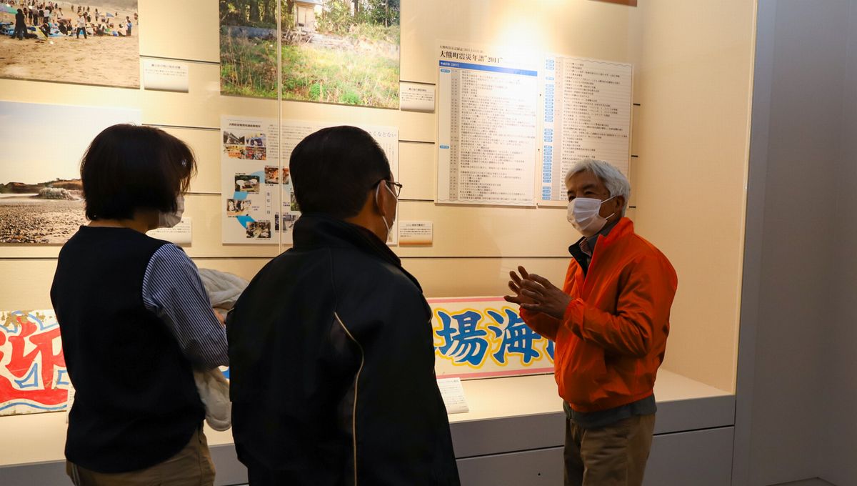 来場者に町の状況を説明する鈴木さん(右)
