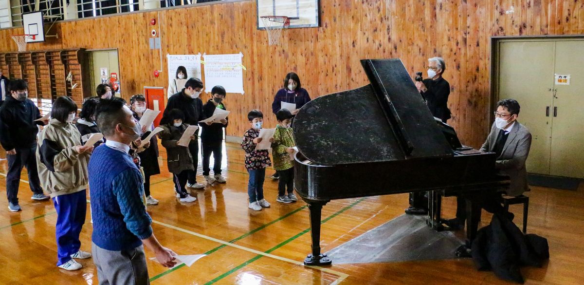関口さん(右)から発声方法を教わる子どもたち