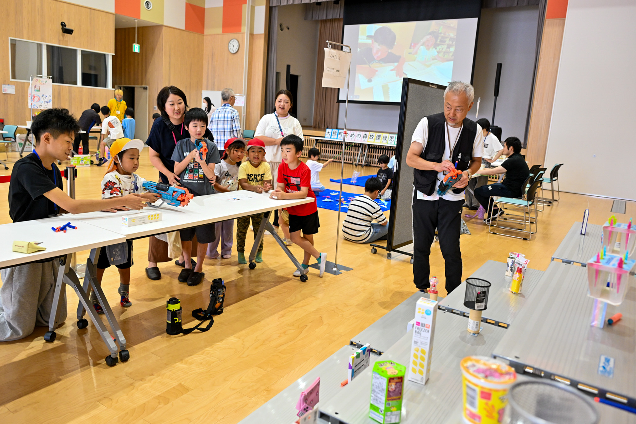 射的ゲームで景品に狙いを定める子どもたち