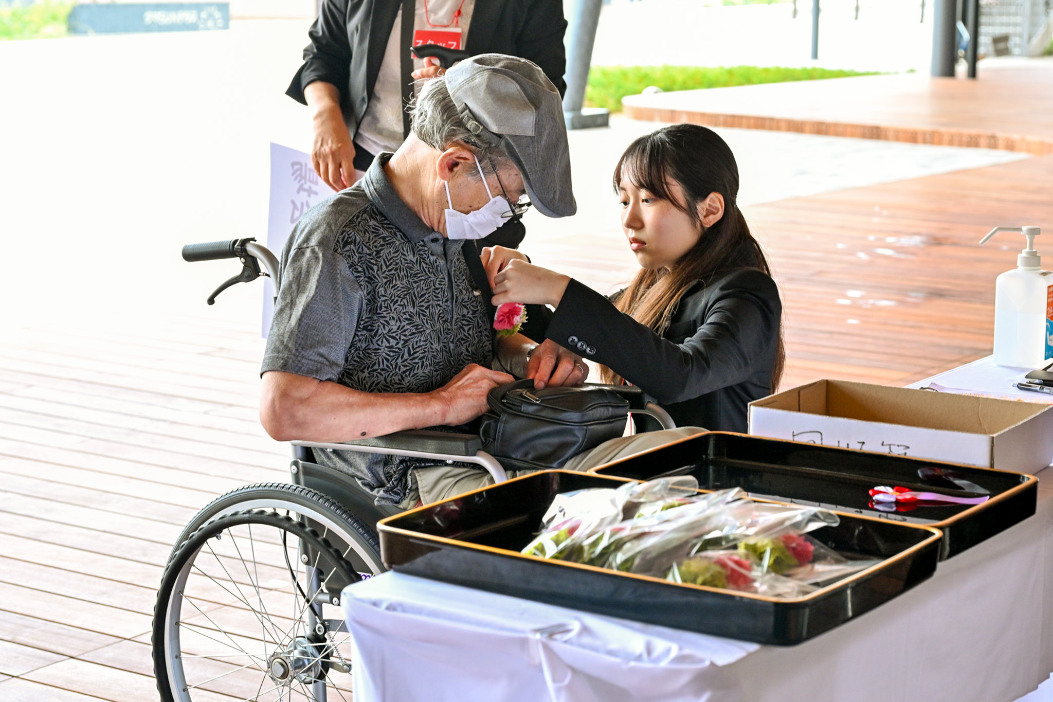 令和7年度、大熊町の70歳以上の方は2,224人（男性987人、女性1,237人／9月1日現在）。写真は、胸にリボンをつけてもらう出席者の様子です。