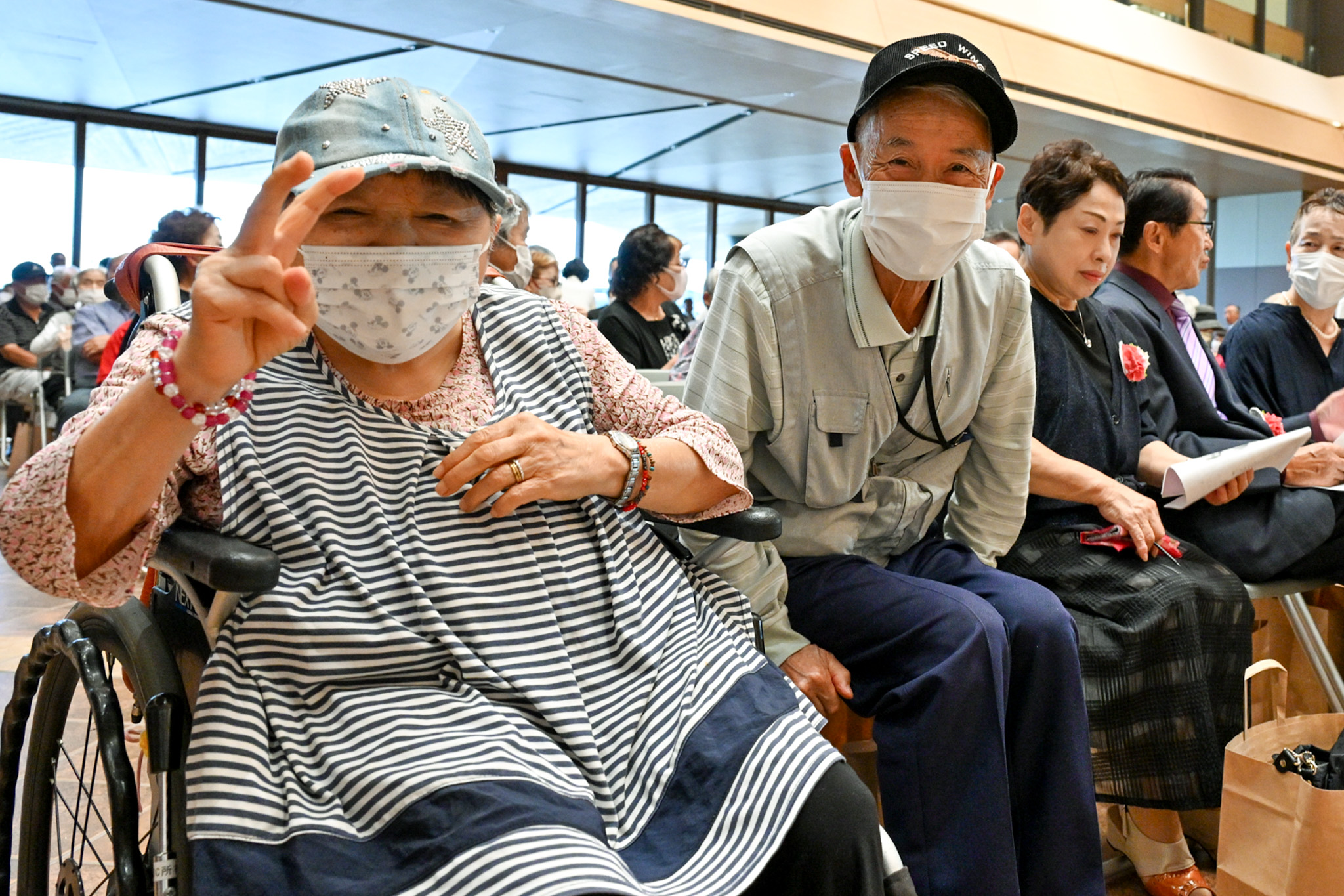 ピースサインをする女性と、隣でほほ笑む男性。出席者の表情には、再会の喜びがあふれています。