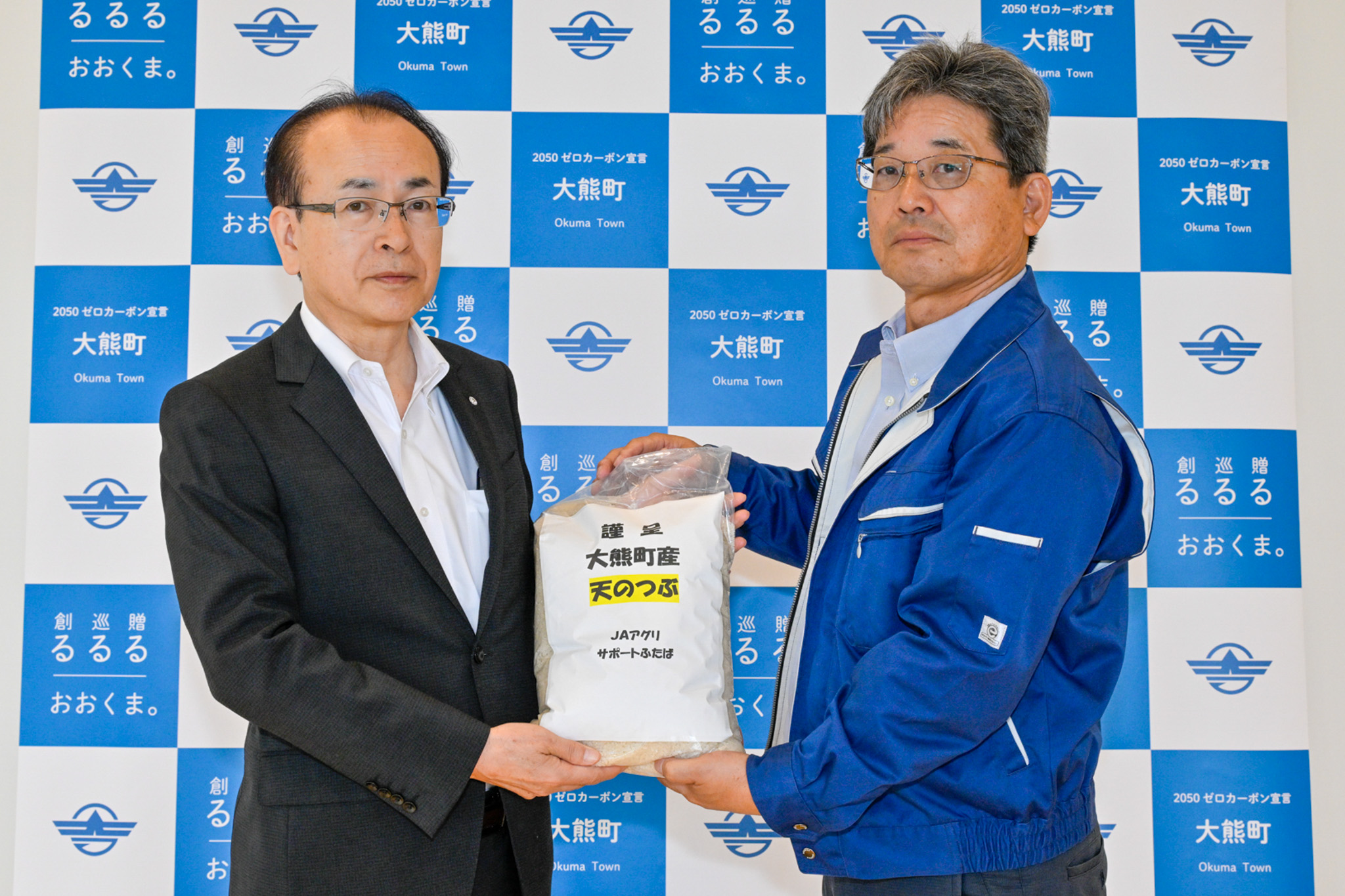町内産天のつぶを手渡した榎本代表（右）
