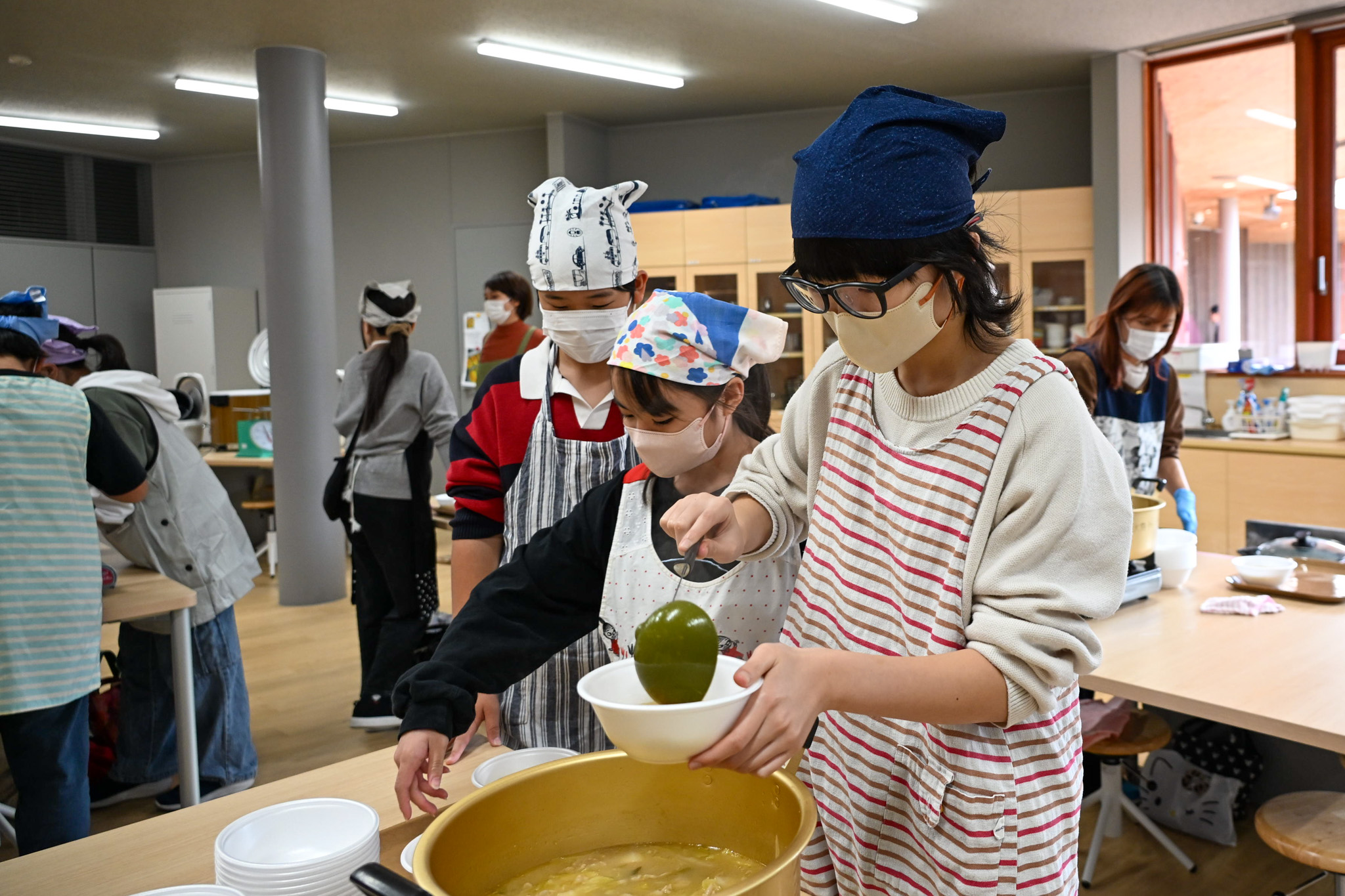 でき上がった豚汁をどんぶり容器に分ける様子。食事のひとときまで、あと少し！