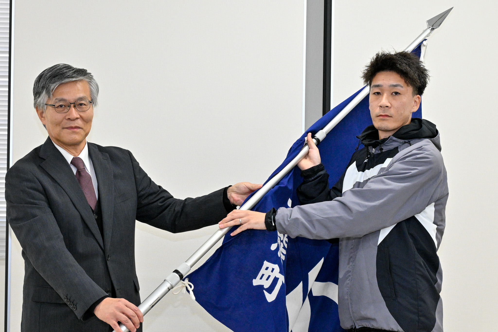 教育長から主将へ町旗が授与される場面