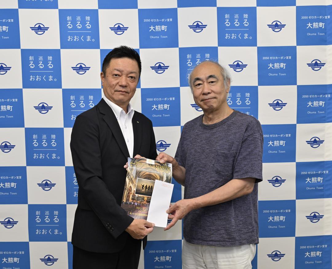 ピースフル・コンサート代表の山本誠一郎さんが吉岡副町長に義援金をお渡ししている様子
